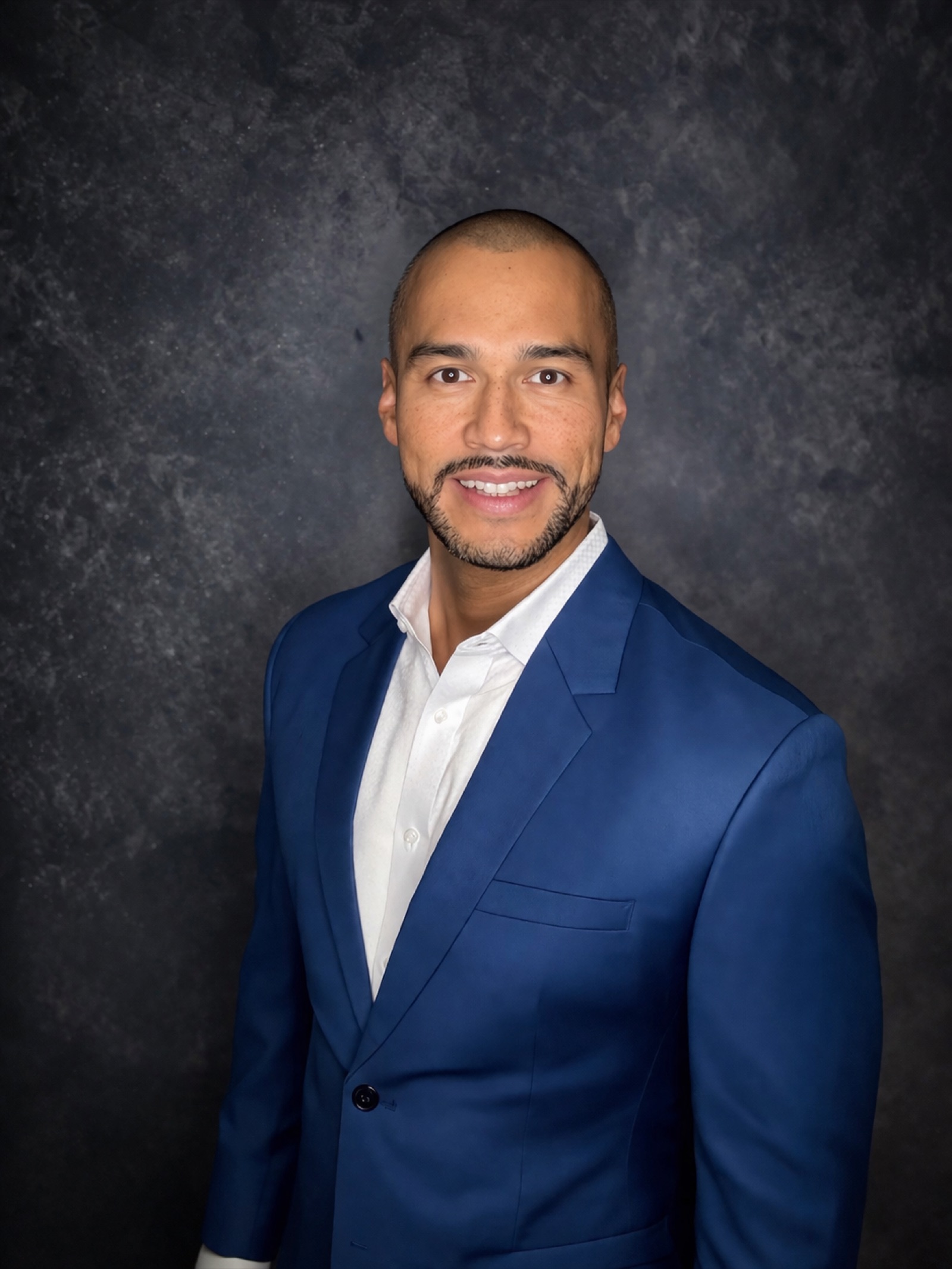 Professional headshot in blue blazer on dark gradient backdrop, photographed at Garfield Local Photo Studio